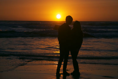 Silhouette woman standing on beach during sunset