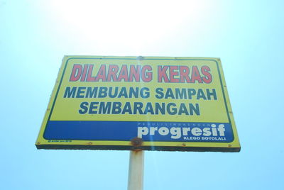 Low angle view of warning sign against clear sky
