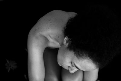 Close-up of shirtless boy against black background