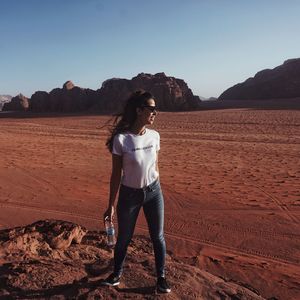 Full length of young woman standing on desert