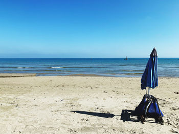 Deck chairs on beach against clear blue sky