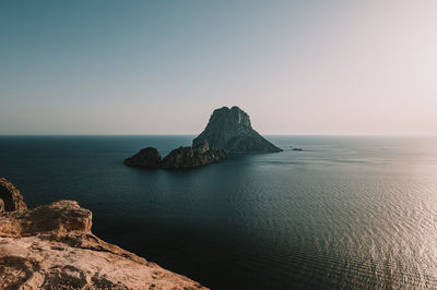 Scenic view of rock formation in sea against clear sky