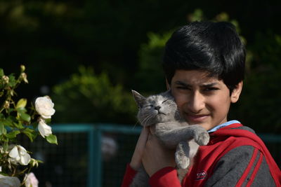 Side view of young woman holding cat