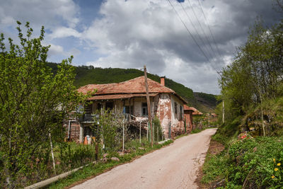 Road amidst trees and buildings against sky