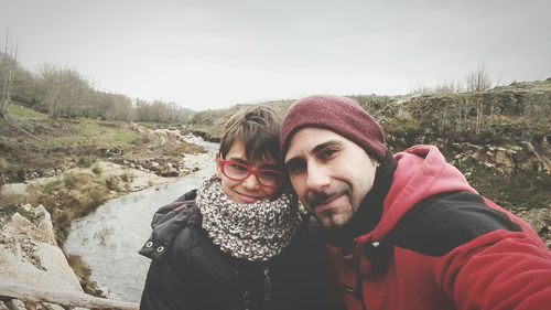 Portrait of father and son in warm cloth on hill against sky