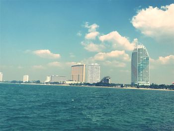 Sea by cityscape against sky
