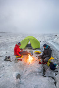 Mountaineers enjoy campfire while camping on a glacier, baffin island