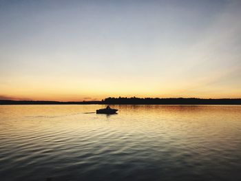 Silhouette boat sailing in lake against sky during sunset