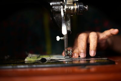 Cropped hand of person working on sewing machine