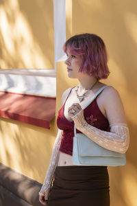 Portrait of young woman standing by railing