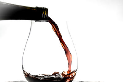 Close-up of wineglass on glass against white background