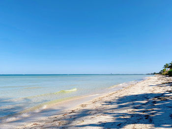 Scenic view of beach against clear blue sky