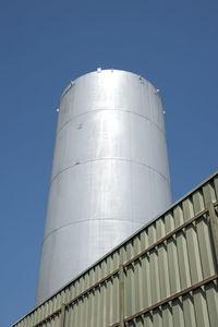 Low angle view of factory against clear blue sky