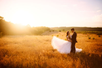 Couple kissing on field against sky