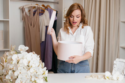 Beautiful girl opens a box on the background of the wardrobe