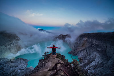 Man standing on rock against sky