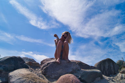 Low angle view of people on rock against sky