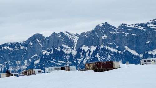 Scenic view of trailer park and snowcapped mountains against cloudy sky