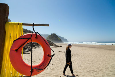 Side view of woman standing on beach against clear sky