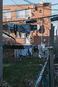 Clothes drying on clothesline by fence against buildings