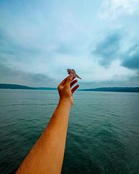 Midsection of person holding sea against sky