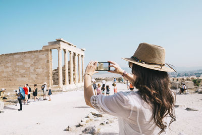 Greece, athens, woman taking a cell phone picture of the erechtheion temple in the acropolis