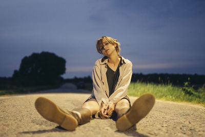 Woman sitting on a country road in a dress