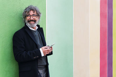 Portrait of young man standing against wall