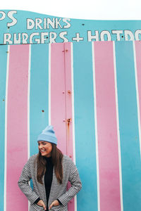 Young woman standing by striped wall