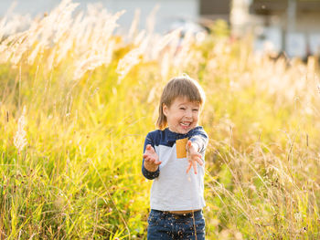 Cute toddler plays in field. smiling boy throws plant seeds in the air. autumn fall season.