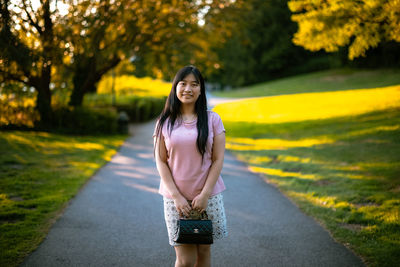 Portrait of woman standing on road against trees