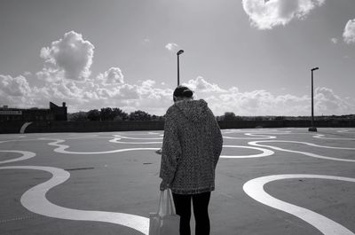 Rear view of man standing by tree against sky