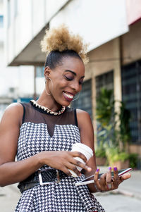 Smiling woman standing holding a shelf and a box of milk outside.