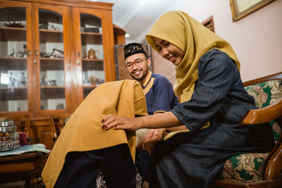 Daughter keeling while showing respect to mother at home