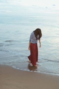 Woman standing on beach against sea