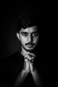 Portrait of young man against black background