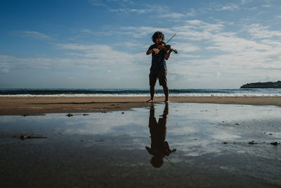 Full length of woman standing on beach against sky