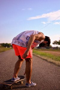 Side view of man standing by road against sky