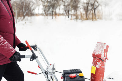 Low section of man working on snow covered field