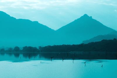 Scenic view of lake by mountains against sky