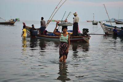 Rear view of people on sea against sky