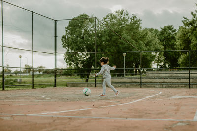 Side view of girl playing football in ground