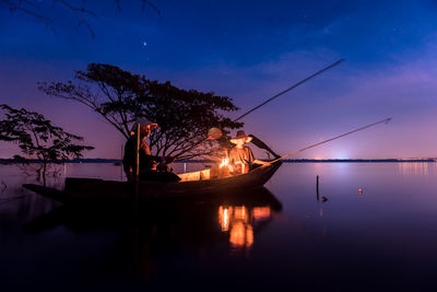 People fishing in lake at dusk