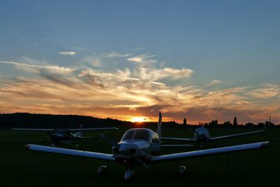 View of airplane at airport runway against sky during sunset