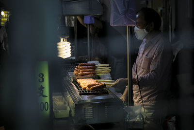 Man preparing sausages on barbecue grill in market