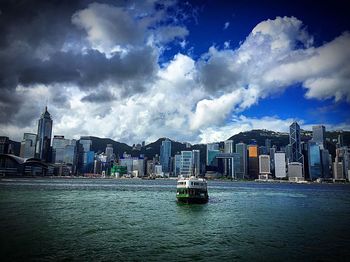 View of city at waterfront against cloudy sky