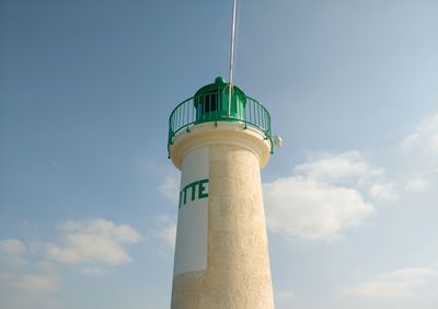 Low angle view of lighthouse by building against sky