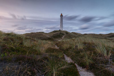 Lighthouse on field against sky