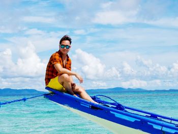 Man sitting on boat in sea against sky