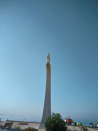 Low angle view of statue against building against clear blue sky